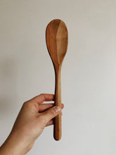 Load image into Gallery viewer, A wooden handcarved cooking spoon with medium wood and light wood held up against a white wall