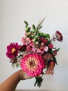 Miscellany + Co's Local Flower Bouquet subscription - a colorful monotone bouquet with barbie pink, hot pink, and light pink tones held up against a beige wall