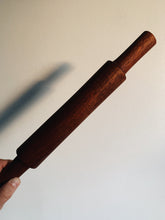 Load image into Gallery viewer, French Rolling Pin in a rich brown wood held up against a white wall