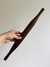 Load image into Gallery viewer, A hand holds a mahogany wood rolling pin against a cream wall