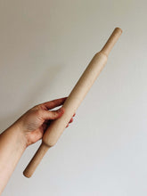 Load image into Gallery viewer, A hand holds a maple wood rolling pin against a cream wall