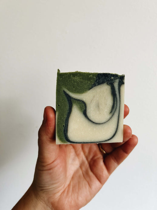 A natural soap bar colored in green, black, and white color swirled together