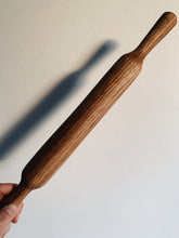 Load image into Gallery viewer, French Rolling Pin in a light brown wood held up against a white wall