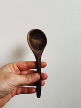 Load image into Gallery viewer, Hand holding a dark brown wooden spoon against a plain background